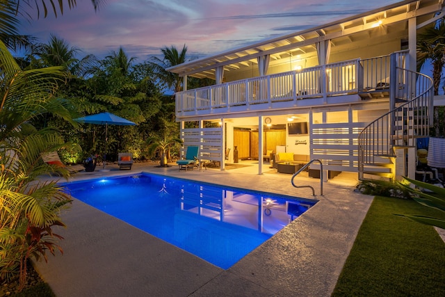 pool at dusk with an outdoor hangout area and a patio