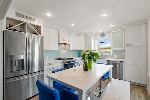 kitchen featuring appliances with stainless steel finishes, a breakfast bar, white cabinets, a center island, and light stone counters