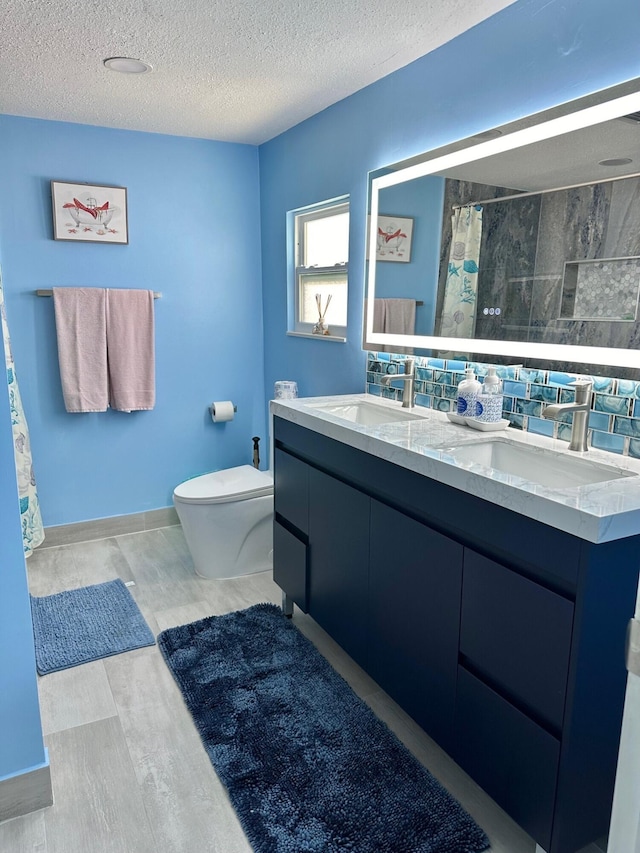 bathroom with vanity, toilet, a shower with shower curtain, and a textured ceiling