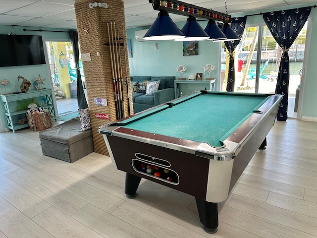 recreation room featuring a drop ceiling, a healthy amount of sunlight, and light wood-type flooring