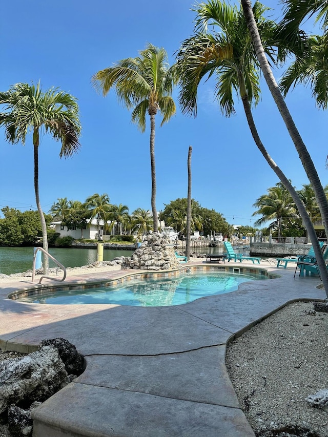 view of pool featuring a water view and a patio