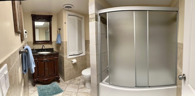 full bathroom featuring tile walls, enclosed tub / shower combo, vanity, toilet, and tile patterned floors