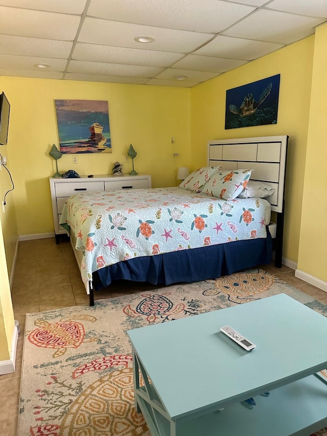 bedroom with a drop ceiling and light tile patterned flooring