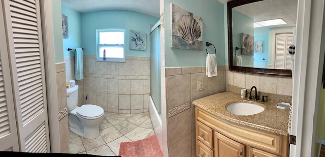 bathroom with vanity, toilet, and tile walls