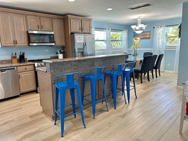 kitchen featuring a kitchen bar, a wealth of natural light, a center island, and appliances with stainless steel finishes