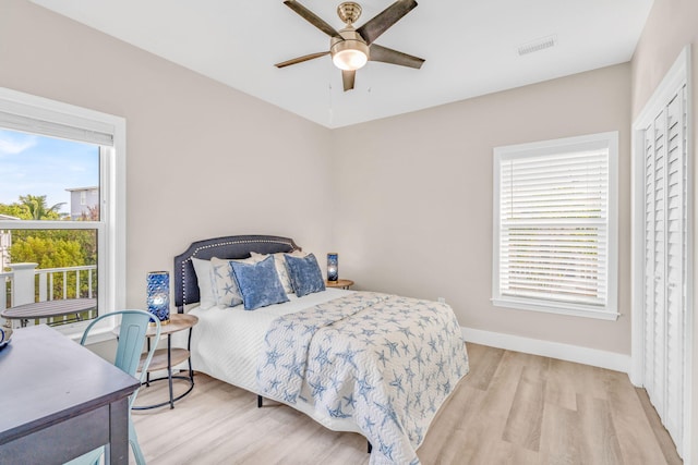 bedroom with light wood-style floors, visible vents, ceiling fan, and baseboards