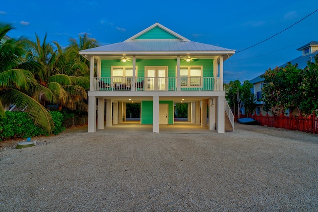 back of house featuring driveway, ceiling fan, stairway, covered porch, and a carport