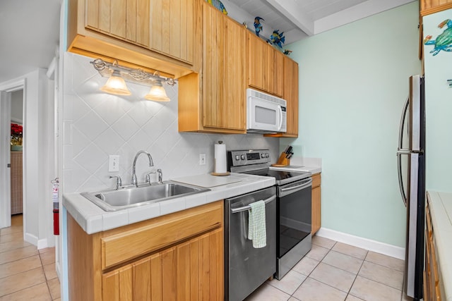 kitchen with stainless steel appliances, tasteful backsplash, sink, and light tile patterned floors