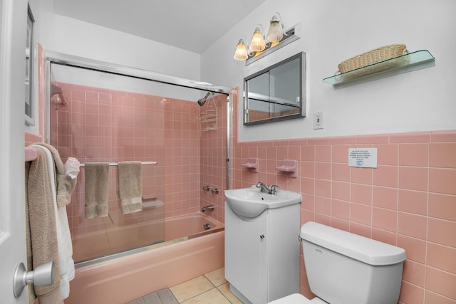 full bathroom with tile walls, tile patterned flooring, enclosed tub / shower combo, vanity, and toilet