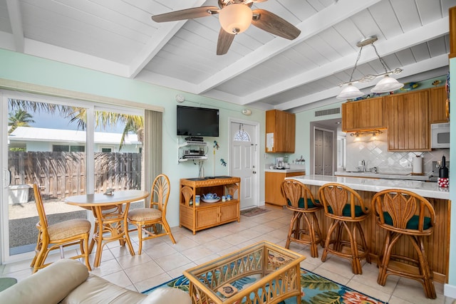 kitchen featuring backsplash, light tile patterned floors, kitchen peninsula, and beamed ceiling