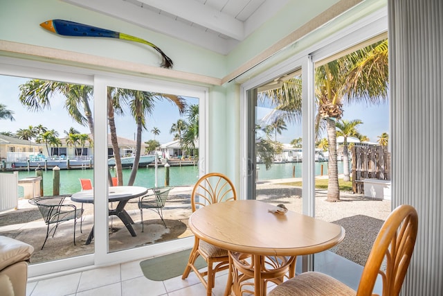 sunroom / solarium featuring beam ceiling and a water view