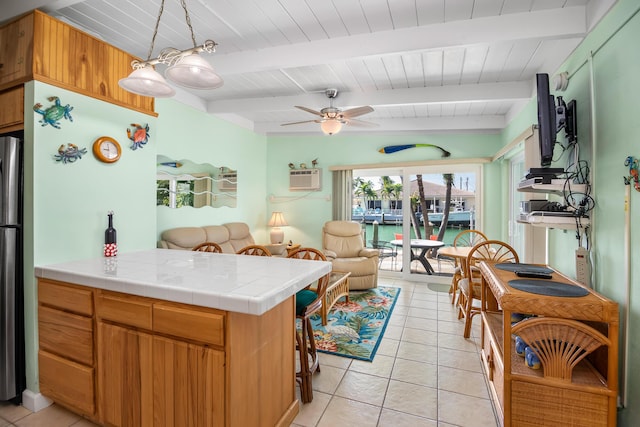 kitchen with pendant lighting, tile counters, kitchen peninsula, and beamed ceiling