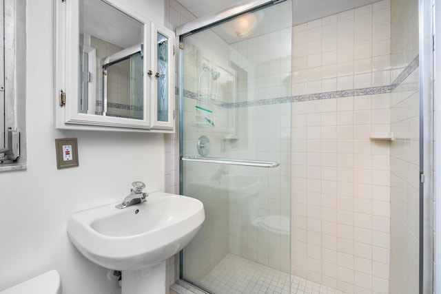 bathroom featuring toilet, a shower with shower door, and sink