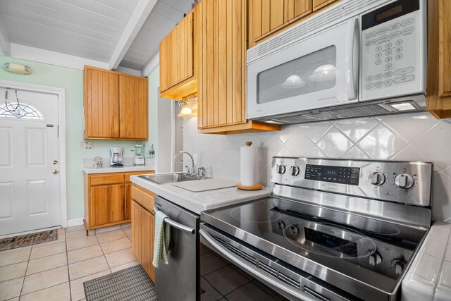 kitchen featuring sink, light tile patterned floors, appliances with stainless steel finishes, lofted ceiling with beams, and decorative backsplash