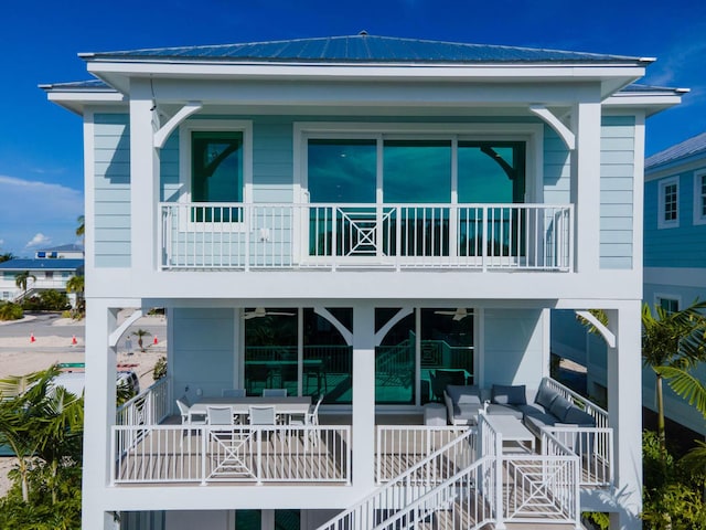 back of property featuring a balcony, metal roof, and stairs