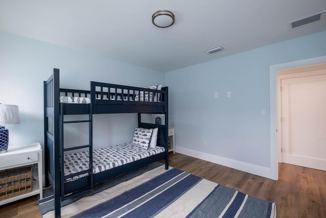 bedroom with baseboards, visible vents, and wood finished floors