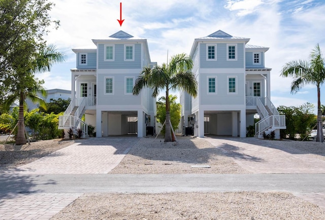 beach home featuring decorative driveway, stairway, a porch, and a carport