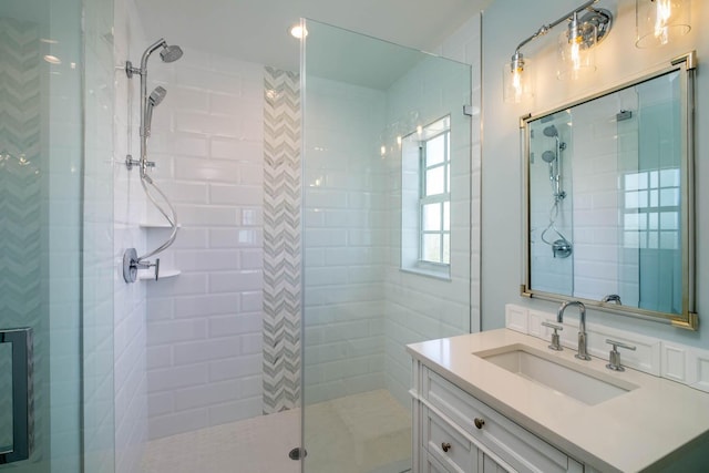full bath featuring tiled shower and vanity