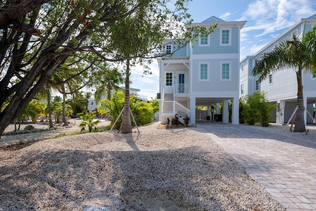 coastal inspired home with stairs, driveway, a carport, and a porch