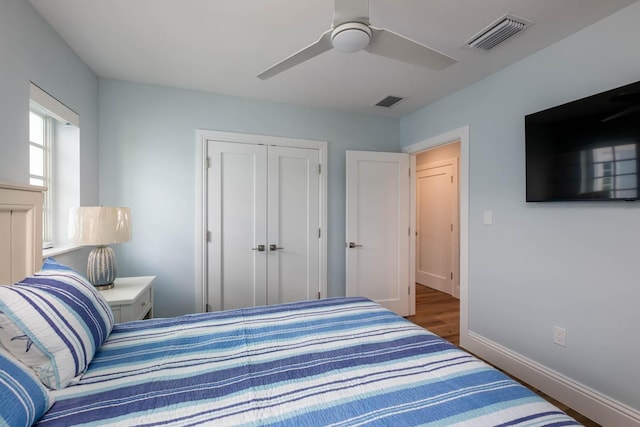 bedroom featuring baseboards, visible vents, a ceiling fan, a closet, and wood finished floors