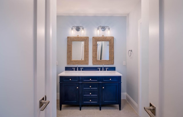 bathroom with baseboards, double vanity, a sink, and tile patterned floors