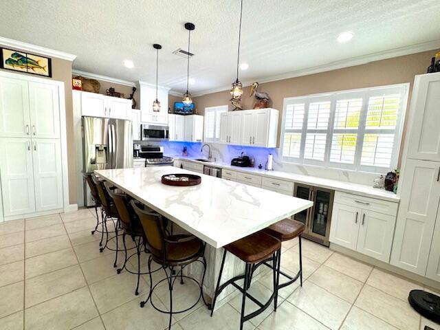 17 N Dr, Key Largo, FL 33037 - kitchen with a breakfast bar area, crown molding, a sink, beverage cooler, and stainless steel appliances