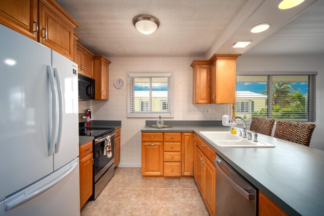 kitchen featuring a healthy amount of sunlight, appliances with stainless steel finishes, sink, and light tile patterned floors