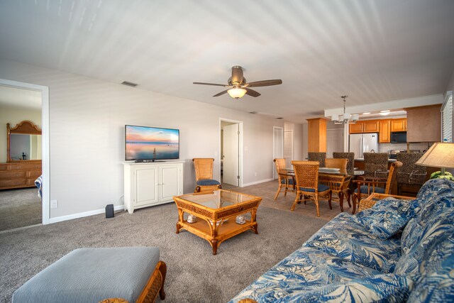 carpeted living room featuring ceiling fan with notable chandelier