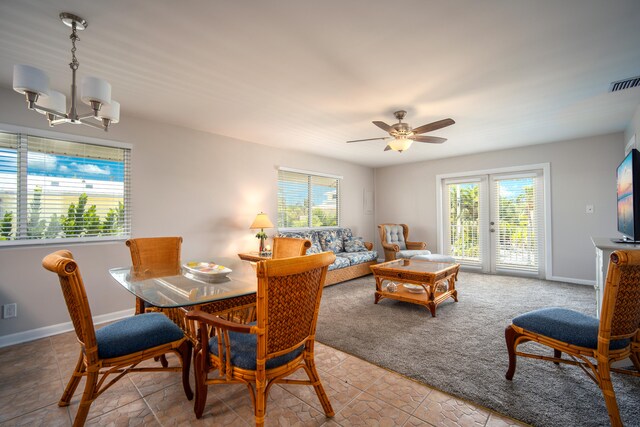 dining area featuring ceiling fan with notable chandelier and light carpet