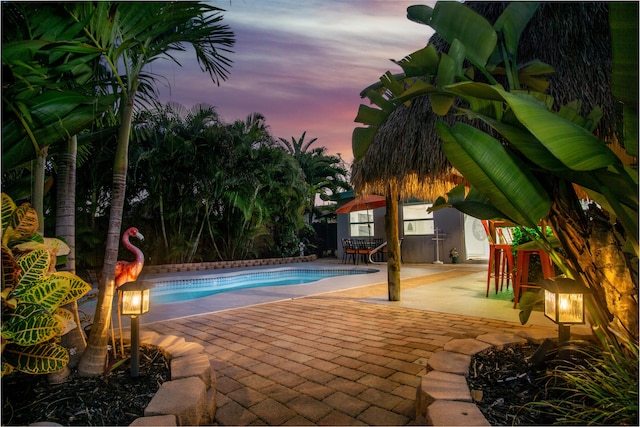 pool at dusk with a patio area