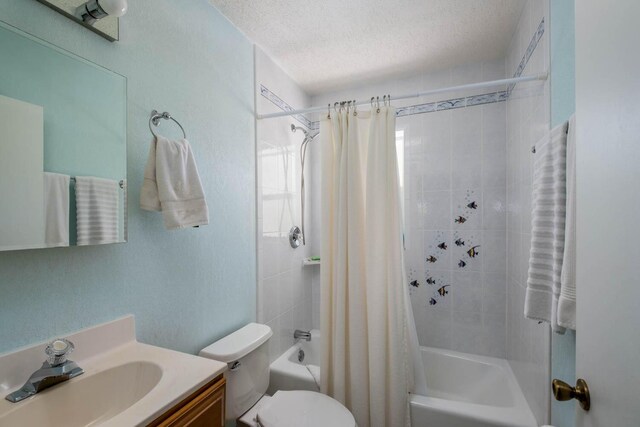 full bathroom with shower / bath combination with curtain, vanity, toilet, and a textured ceiling