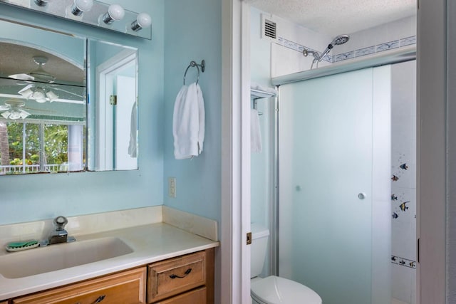 bathroom featuring vanity, ceiling fan, a textured ceiling, and toilet