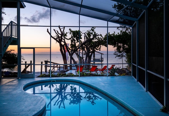 pool at dusk with a water view and glass enclosure