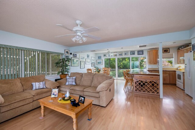 living room with a textured ceiling, light hardwood / wood-style floors, and ceiling fan