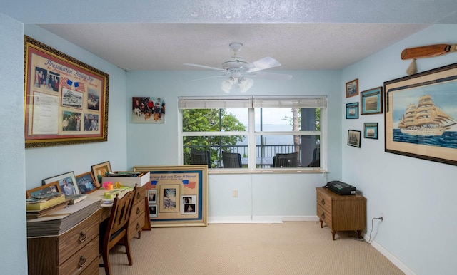 office area with light carpet, ceiling fan, and a textured ceiling