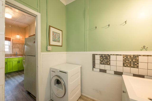 washroom featuring tile walls, sink, washer / dryer, and dark hardwood / wood-style floors