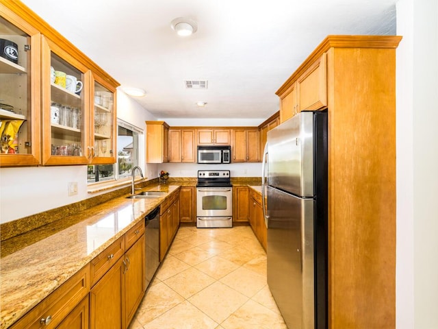 kitchen featuring light stone counters, appliances with stainless steel finishes, sink, and light tile patterned floors