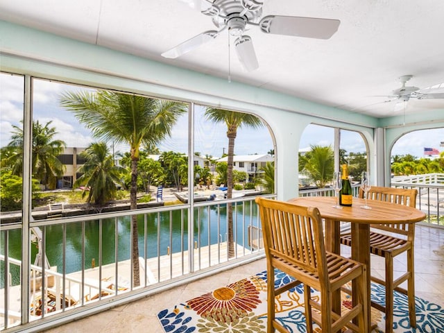 sunroom / solarium featuring ceiling fan and a water view