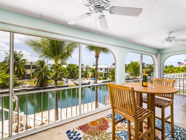 sunroom / solarium featuring ceiling fan and a water view