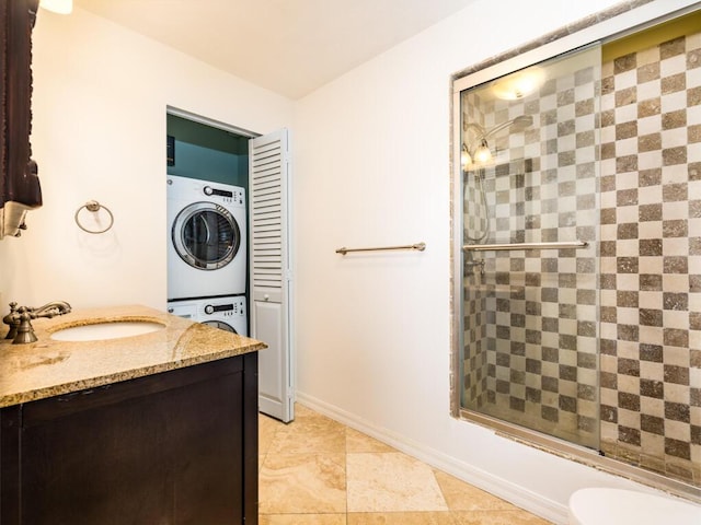 full bathroom with stacked washer / drying machine, toilet, combined bath / shower with glass door, and vanity