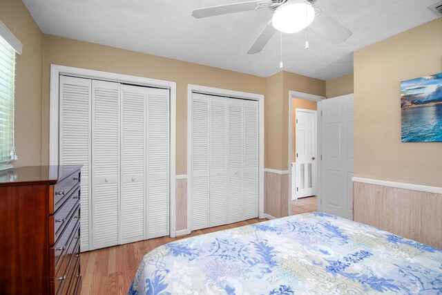 bedroom featuring visible vents, light wood-style flooring, multiple closets, and ceiling fan
