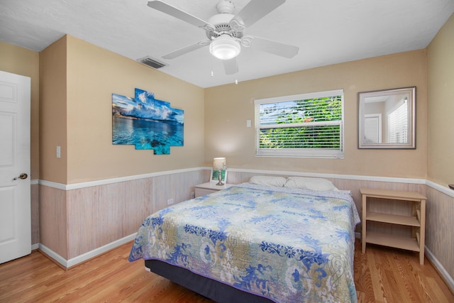 bedroom featuring wood finished floors, visible vents, and wainscoting