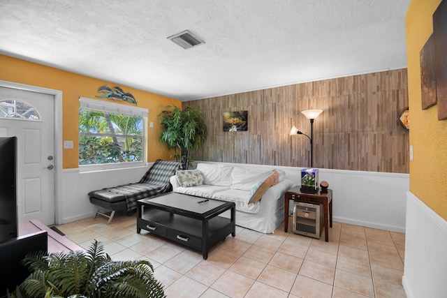 living room featuring visible vents, a textured ceiling, wainscoting, and tile patterned flooring