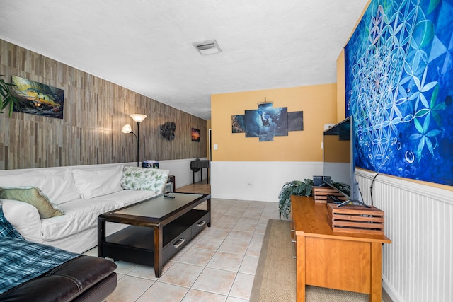 living room with tile patterned flooring, visible vents, and wainscoting