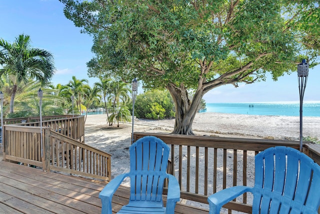 wooden deck featuring a view of the beach and a water view