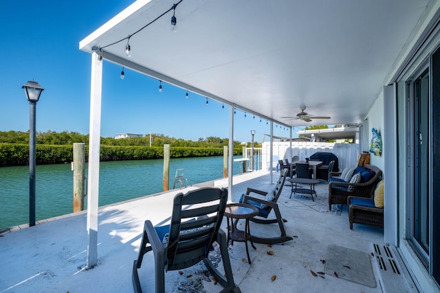 view of patio / terrace with a water view, ceiling fan, and a dock