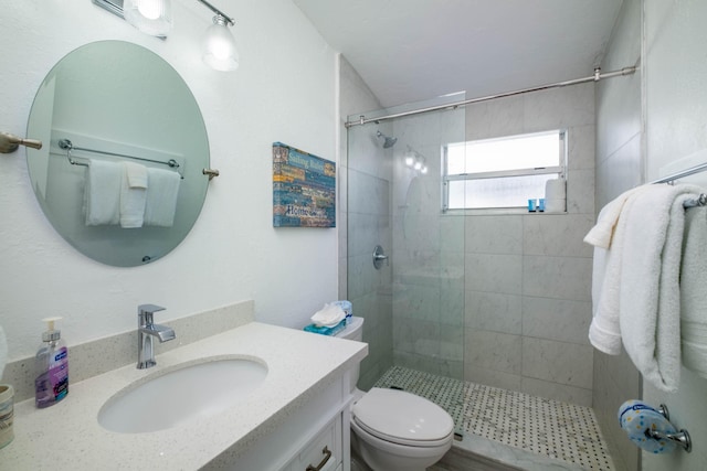 bathroom with vanity, toilet, and a tile shower