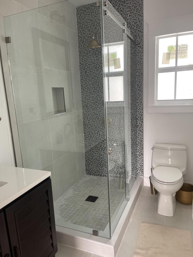 bathroom with vanity, toilet, a shower with shower door, and tile patterned flooring