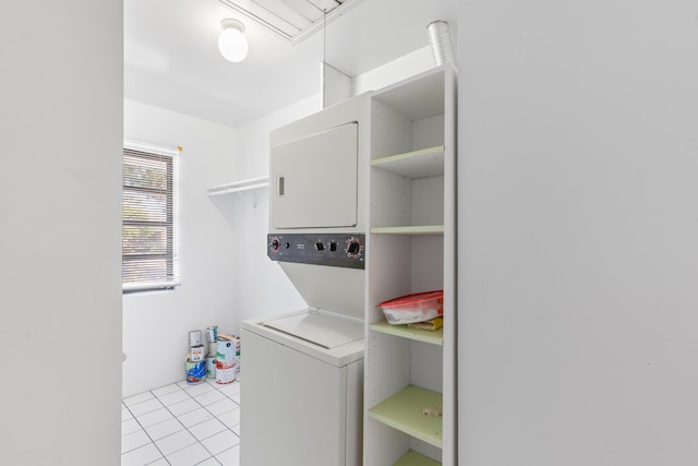 laundry area with stacked washer / drying machine and light tile patterned floors