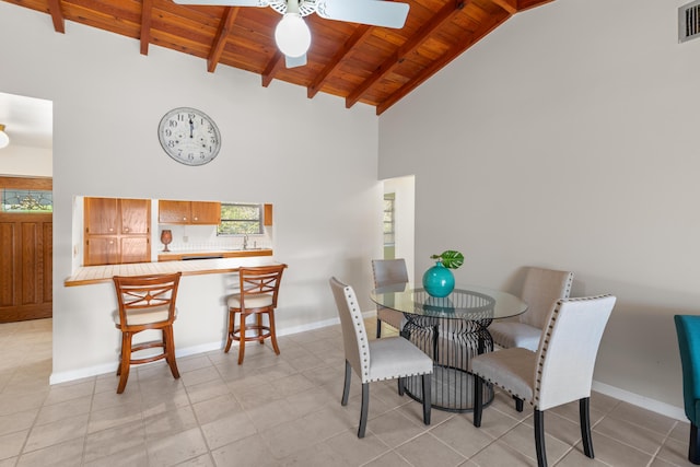 tiled dining space with sink, wood ceiling, high vaulted ceiling, and beamed ceiling